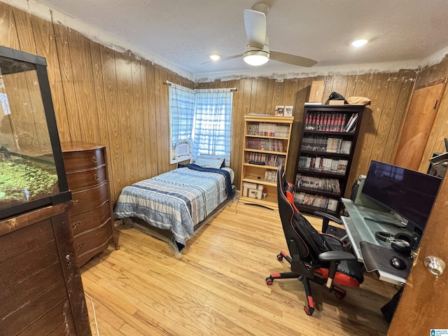 bedroom featuring wooden walls, a ceiling fan, and wood finished floors