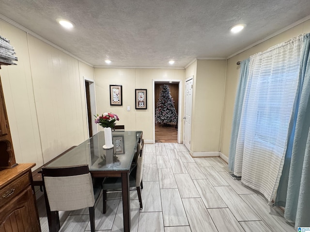 dining space featuring baseboards, a textured ceiling, ornamental molding, and wood tiled floor