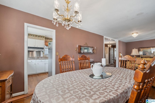 dining area with a notable chandelier, baseboards, and wood finished floors