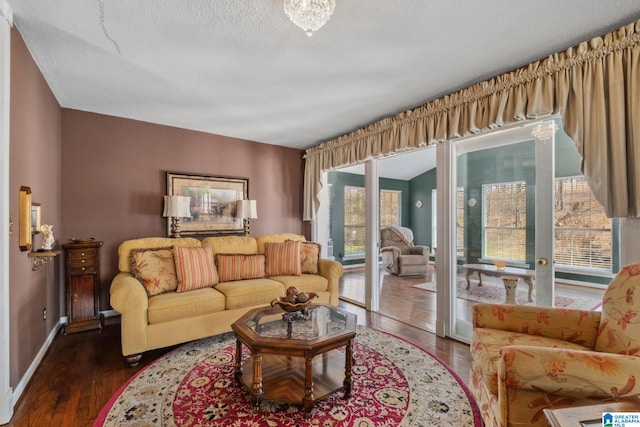 living area with baseboards, a textured ceiling, and wood finished floors