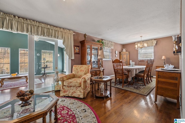 dining room with a chandelier, baseboards, a textured ceiling, and wood finished floors