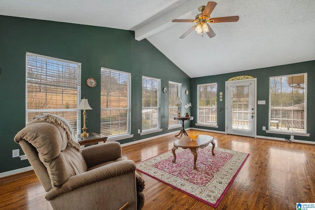 living room featuring plenty of natural light, vaulted ceiling with beams, baseboards, and wood finished floors