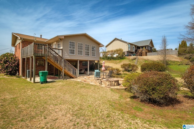 rear view of house featuring an outdoor fire pit, a yard, brick siding, stairs, and a patio area