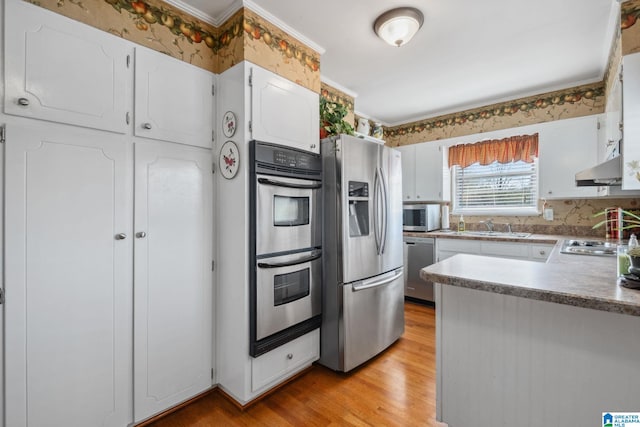 kitchen with under cabinet range hood, light wood-style flooring, stainless steel appliances, white cabinetry, and a sink