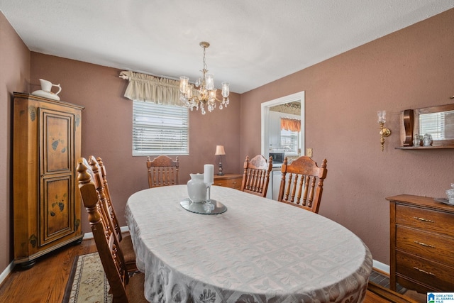 dining room with a notable chandelier, plenty of natural light, dark wood-style floors, and baseboards