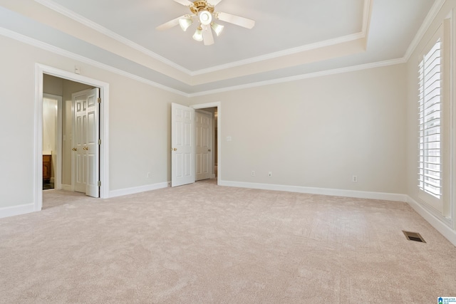 empty room featuring a tray ceiling, visible vents, light carpet, and baseboards