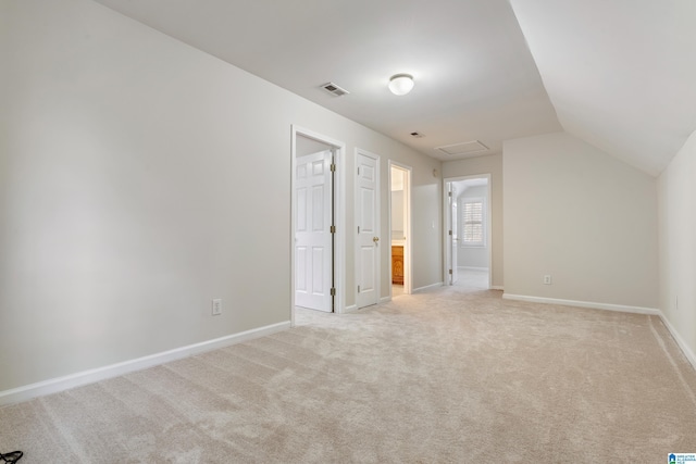 unfurnished bedroom featuring light carpet, visible vents, lofted ceiling, and baseboards