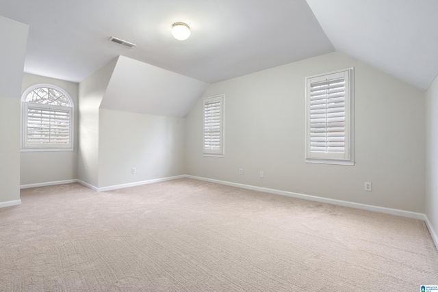 bonus room with visible vents, light carpet, baseboards, and vaulted ceiling