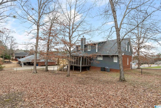 rear view of property with fence, roof with shingles, a sunroom, central AC unit, and a chimney