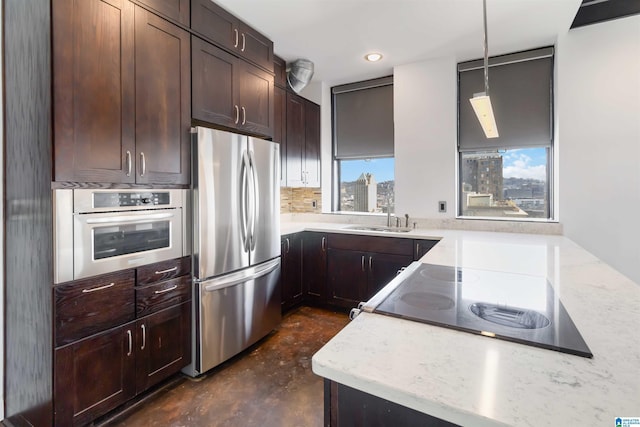 kitchen featuring light stone countertops, a sink, dark brown cabinets, concrete flooring, and appliances with stainless steel finishes