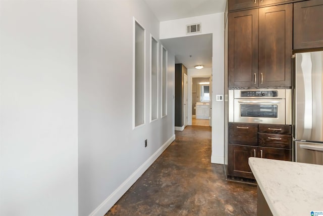 kitchen featuring visible vents, light stone counters, appliances with stainless steel finishes, baseboards, and concrete flooring