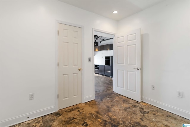 spare room featuring concrete flooring and baseboards