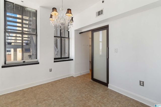 empty room featuring visible vents, baseboards, and a notable chandelier