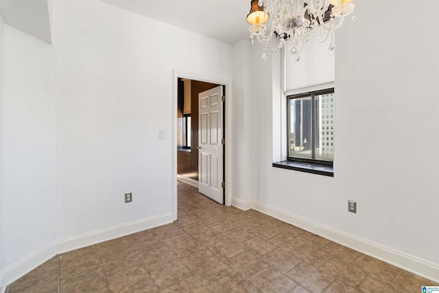 empty room featuring baseboards and an inviting chandelier