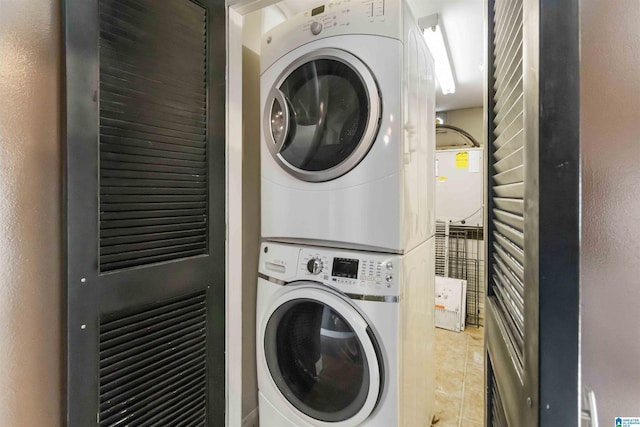 clothes washing area with tile patterned floors, stacked washer / drying machine, and laundry area