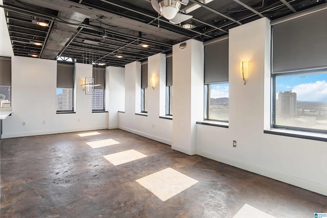 unfurnished room with baseboards and concrete flooring