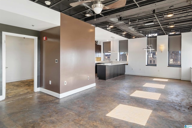 unfurnished living room featuring baseboards, concrete flooring, and ceiling fan