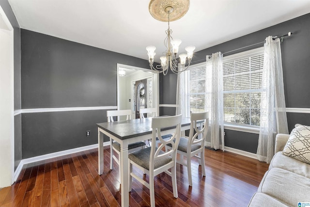 dining room with a notable chandelier, baseboards, and wood-type flooring