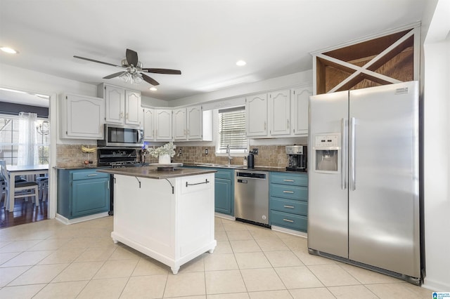 kitchen with dark countertops, blue cabinetry, backsplash, and appliances with stainless steel finishes