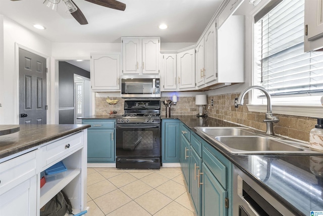 kitchen featuring dark countertops, black gas stove, a sink, white cabinets, and stainless steel microwave