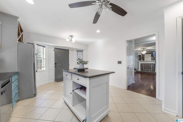 kitchen with open shelves, dark countertops, freestanding refrigerator, light tile patterned flooring, and ceiling fan