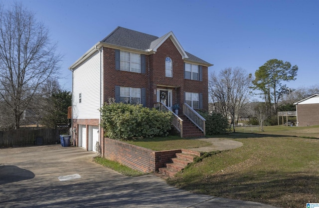 colonial-style house with driveway, fence, an attached garage, a front yard, and brick siding