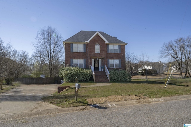 view of front of home with brick siding, a front lawn, and fence