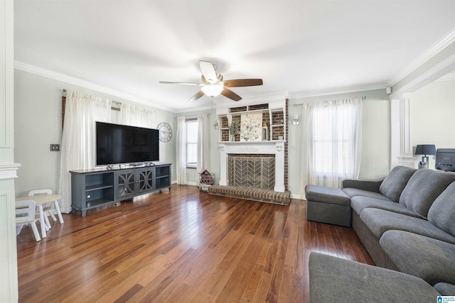 living room featuring a brick fireplace, crown molding, a ceiling fan, and hardwood / wood-style flooring