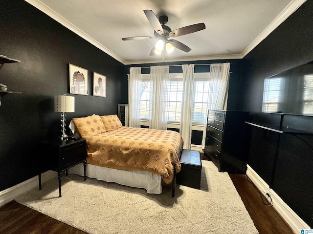 bedroom with multiple windows, wood finished floors, baseboards, and ornamental molding