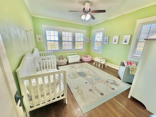 bedroom featuring multiple windows, a crib, and wood finished floors