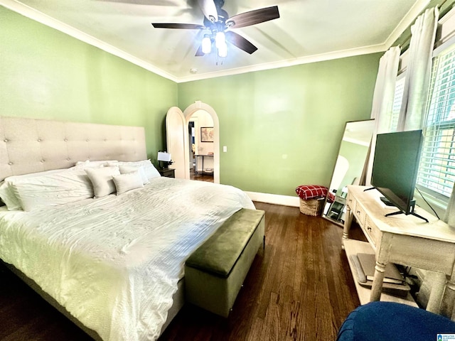 bedroom with ornamental molding, a ceiling fan, dark wood finished floors, arched walkways, and baseboards