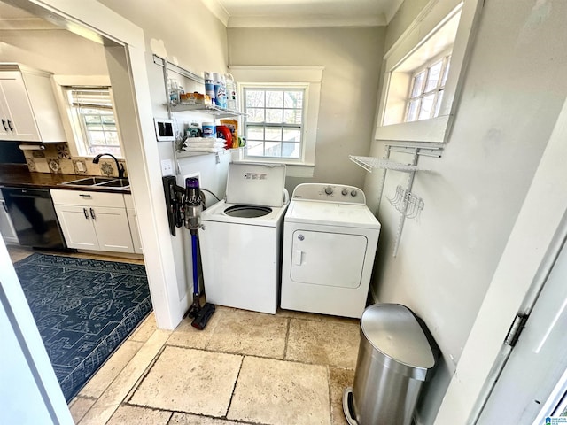 clothes washing area with washing machine and clothes dryer, crown molding, laundry area, stone tile flooring, and a sink