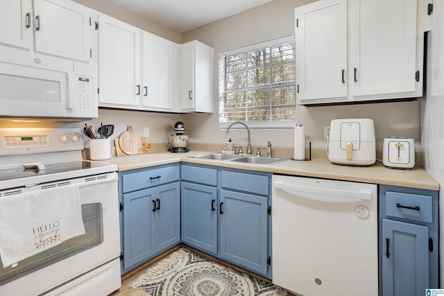 kitchen with blue cabinets, white appliances, light countertops, and a sink