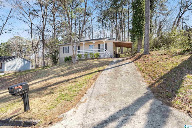 view of front of property featuring a porch, an attached carport, driveway, and a front yard