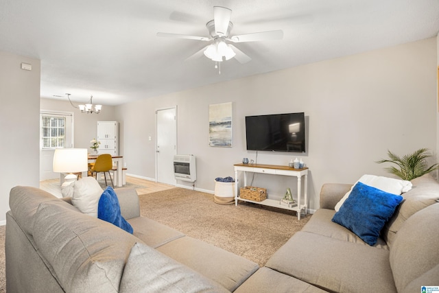 living area featuring heating unit, ceiling fan with notable chandelier, and baseboards