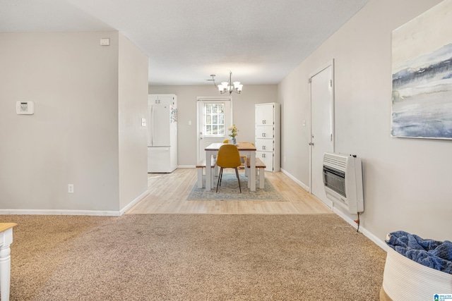 unfurnished dining area with baseboards, heating unit, light colored carpet, and a chandelier