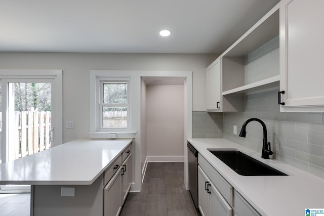 kitchen with dishwasher, open shelves, light countertops, and a sink