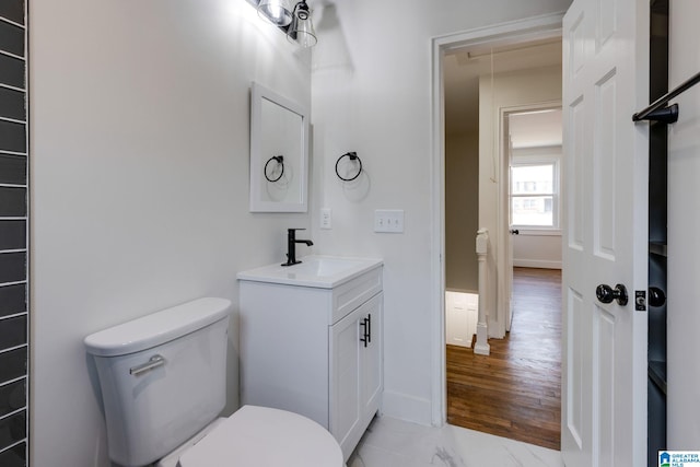 bathroom with baseboards, toilet, marble finish floor, and vanity