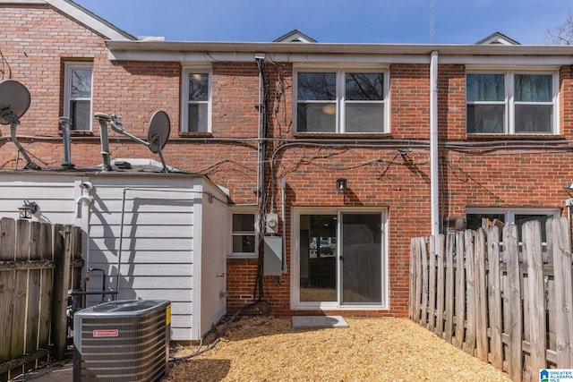 rear view of property with cooling unit, brick siding, and fence