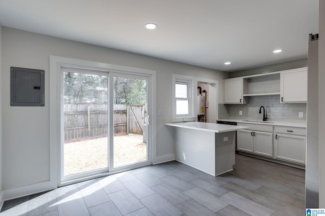 kitchen featuring tasteful backsplash, a sink, electric panel, a peninsula, and open shelves