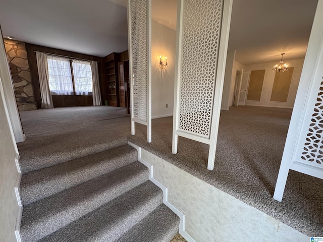 stairs with a notable chandelier and carpet flooring