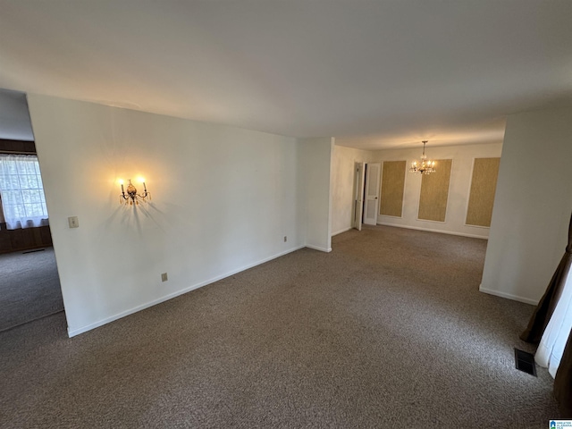 unfurnished room with visible vents, a notable chandelier, carpet, and baseboards