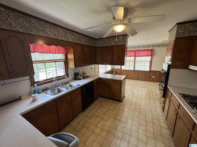 kitchen featuring light floors, a wainscoted wall, a sink, black appliances, and light countertops