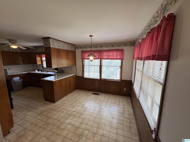 kitchen with wooden walls, a peninsula, wainscoting, light countertops, and light floors