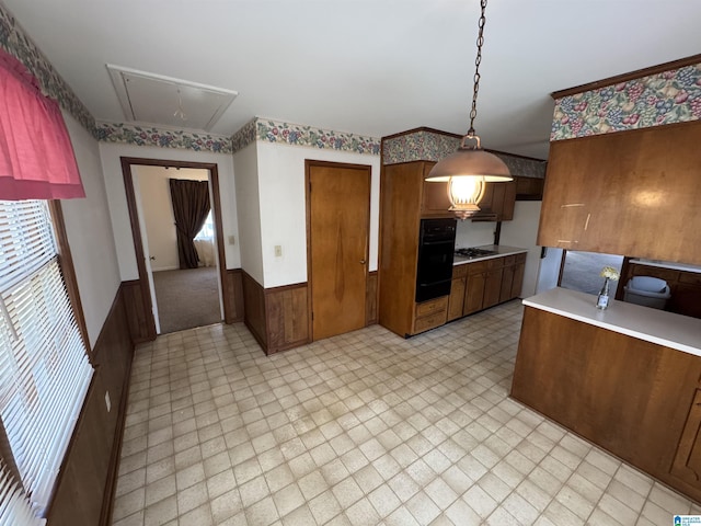 kitchen featuring oven, a wainscoted wall, light floors, light countertops, and brown cabinets