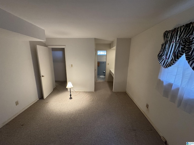 unfurnished bedroom featuring baseboards, ensuite bathroom, and carpet