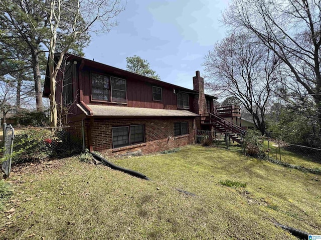 back of property with stairs, fence, a yard, brick siding, and a chimney