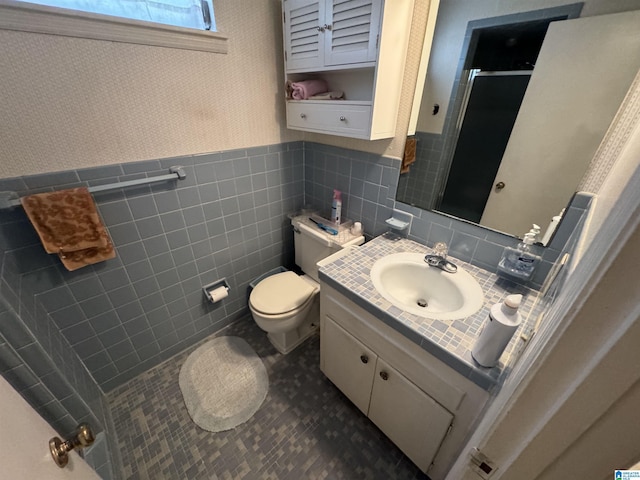 bathroom featuring wallpapered walls, toilet, wainscoting, a stall shower, and vanity