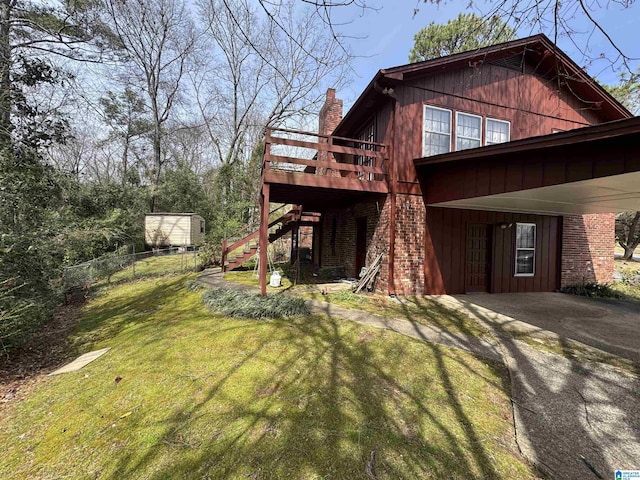 view of home's exterior with a lawn, stairway, a wooden deck, brick siding, and a chimney