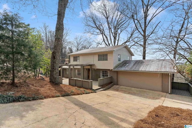 view of front of home with a garage, brick siding, metal roof, and driveway